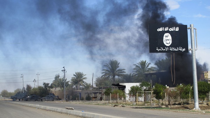 Smoke rises behind an Islamic State flag in Syria in 2014.