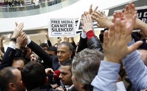 The Zaman editor in chief, Ekrem Dumanli, stands in a crowd of supporters and newspaper employees holding signs that say, in English and Turkish, 