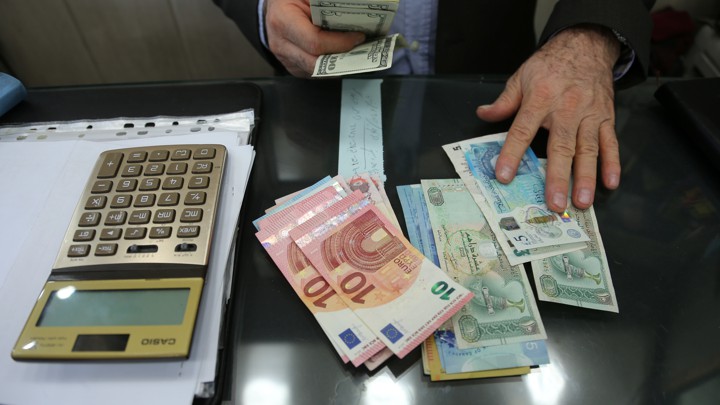 A money changer holds U.S. dollars as he counts other currencies at Tehran's Grand Bazaar on October 14, 2017