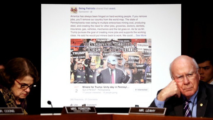 Senators Dianne Feinstein and Pat Leahy sit in front of a screen showing a fake Facebook page created by Russia during the 2016 election.