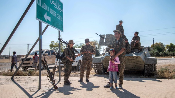 YPG fighters stand with a child near a tank in Raqqa in 2015