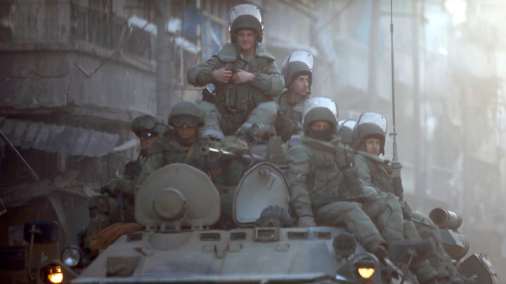 Heavily armed Russian soldiers ride atop an armored tank in Aleppo.
