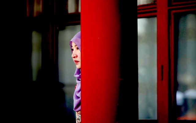 A woman stands behind a pillar during the Eid al-Adha festival at a Chinese mosque.
