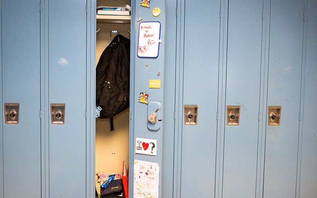 A row of lockers, with one open to show a backpack, textbooks, and interior decorations