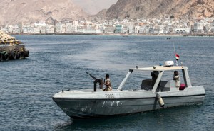 A boat with a Yemeni soldier manning a weapon patrols the coast of the port city Mukalla.