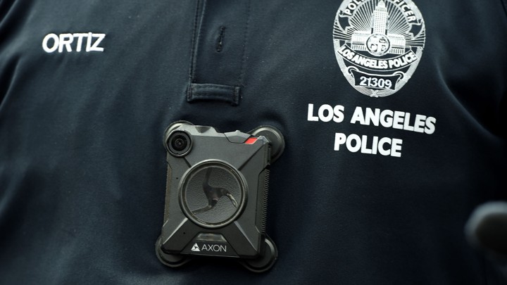 A square black camera on a police officer's black uniform shirt