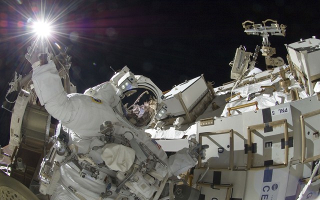 An astronaut works outside the International Space Station.