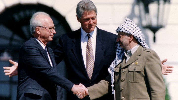 Rabin and Arafat shake hands, with Clinton behind them, on the South Lawn of the White House.