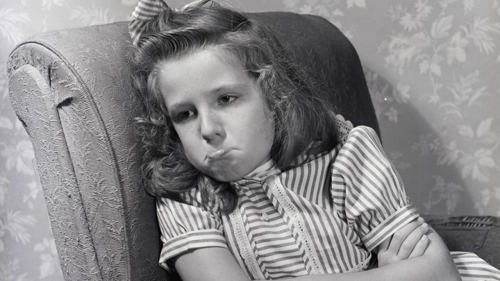 An angry girl pouting in a chair