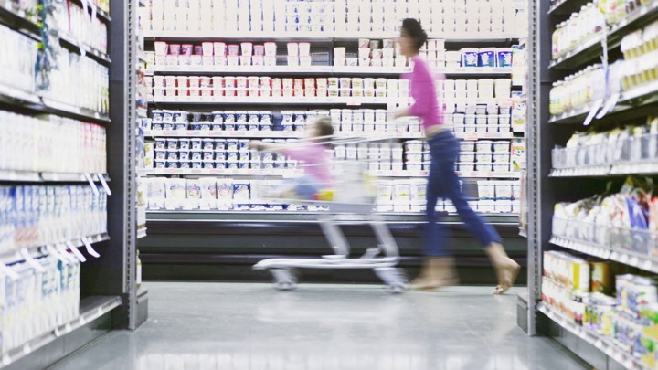 A mother pushes her child through a grocery store