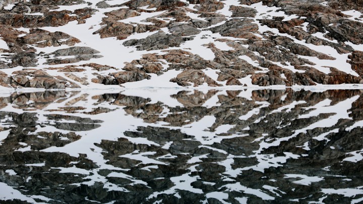 A snow-covered shore reflected in water