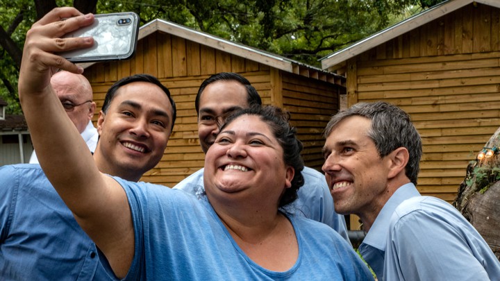 A woman wearing blue takes a selfie with three men also wearing blue