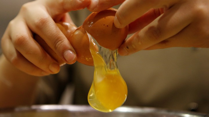 A person cracks an egg.