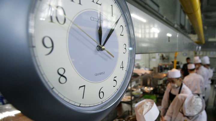 A clock above a busy kitchen