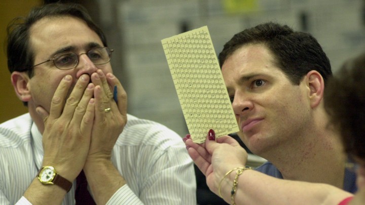 Reporters examine a ballot during a manual recount in Broward County, Florida, in 2000.