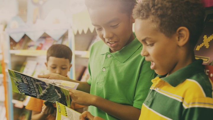 Young children perusing books at a Scholastic book fair