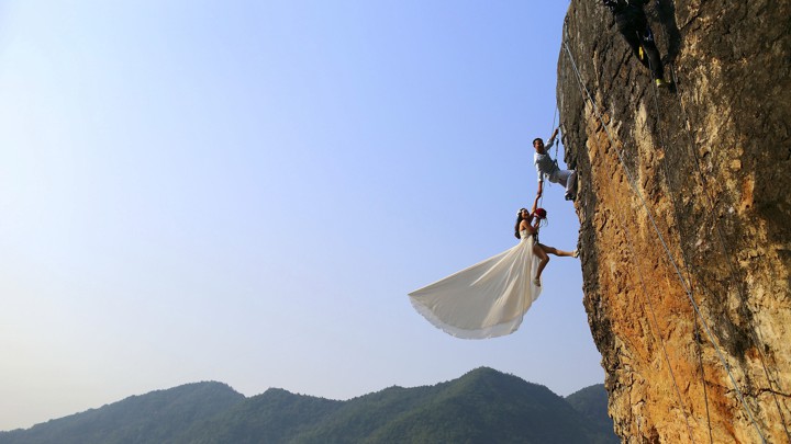 A woman in a wedding dress climbing a mountain