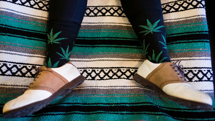 The legs of a person who is wearing socks that feature marijuana leaves