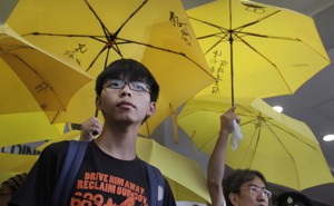 Joshua Wong stands in front of yellow umbrellas, the symbol of the 2014 Hong Kong protests, ahead of a 2015 court hearing.