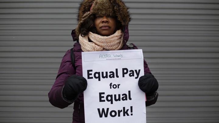 A woman holds a sign saying "Equal pay for equal work"