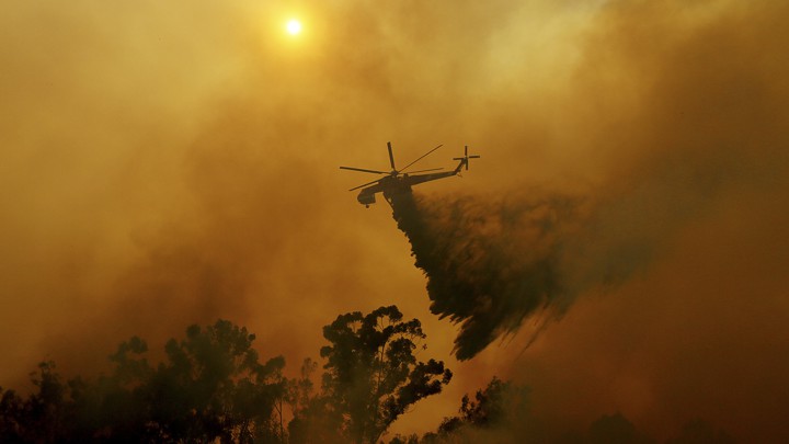 A helicopter drops fire retardant onto a wildfire.