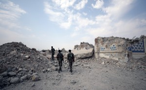 Fighters from Syrian Democratic Forces stand near the destroyed Uwais al-Qarni shrine in Raqqa, Syria.