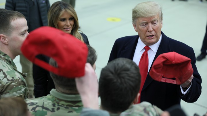 Donald Trump holds a cap while visiting U.S. troops at Ramstein Air Base in Germany on December 27, 2018.