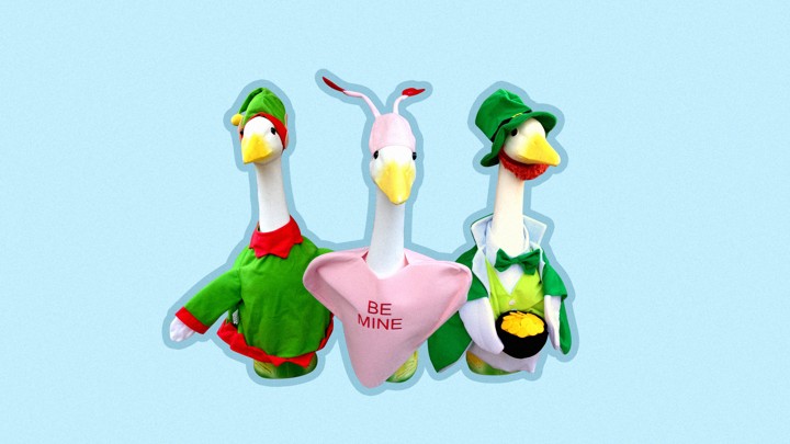 Three statues of geese, dressed in an elf outfit, a heart that says "be mine" and a leprechaun outfit