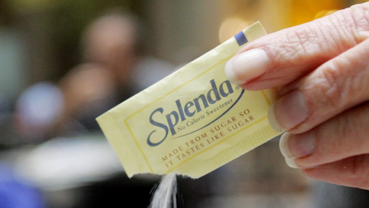 A hand pouring out a packet of Splenda