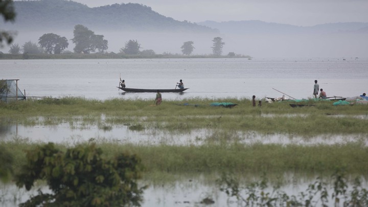 People navigate down a river in a small boat.