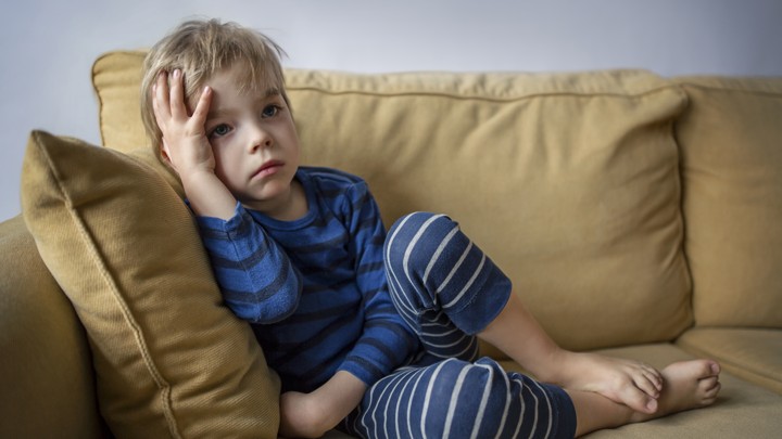 A boy looks bored sitting on a couch