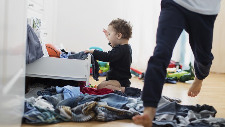 A child pulls clothes out of a drawer.