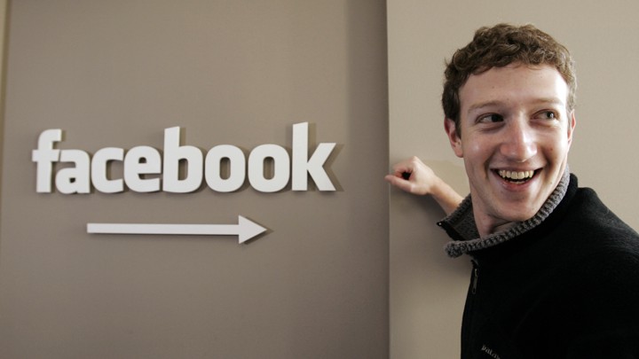 Mark Zuckerberg poses next to a Facebook sign in 2007.