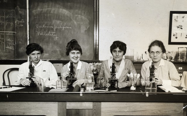 Women seated before microscopes in an undated photo
