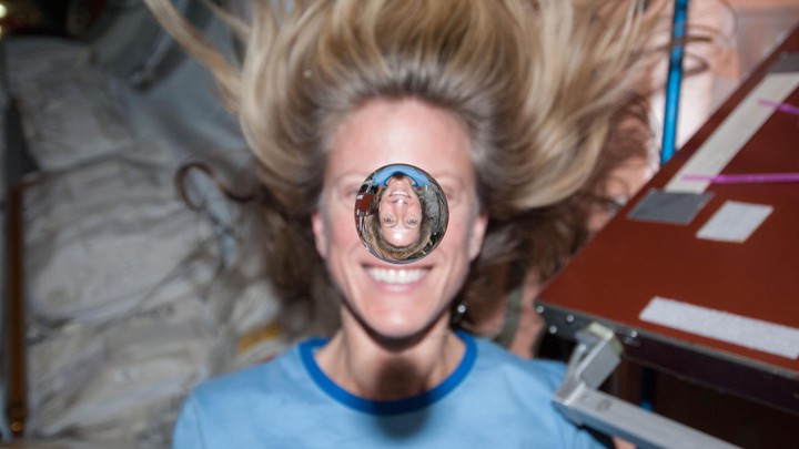 NASA astronaut Karen Nyberg smiles behind a floating bubble of water on the International Space Station