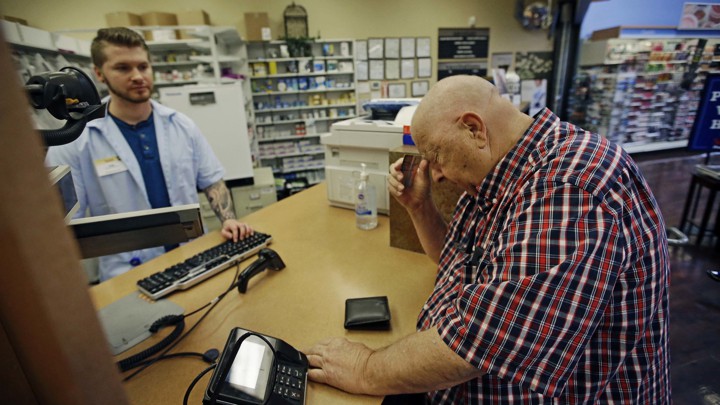 A man picks up prescriptions at a pharmacy.