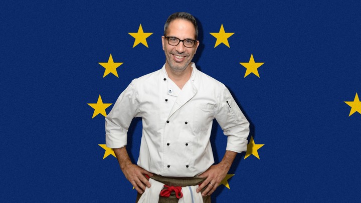 Yotam Ottolenghi stands in front of a European Union flag.