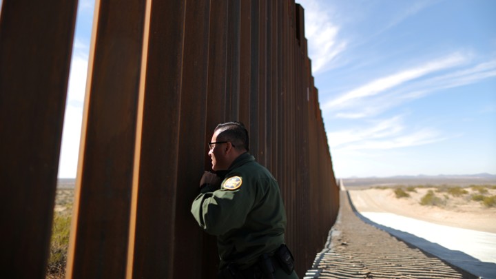 A U.S. Border Patrol agent looks through the U.S.-Mexico border fence in Santa Teresa, New Mexico.