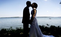 A couple kisses following their wedding ceremony by a lake in Milford, Iowa.