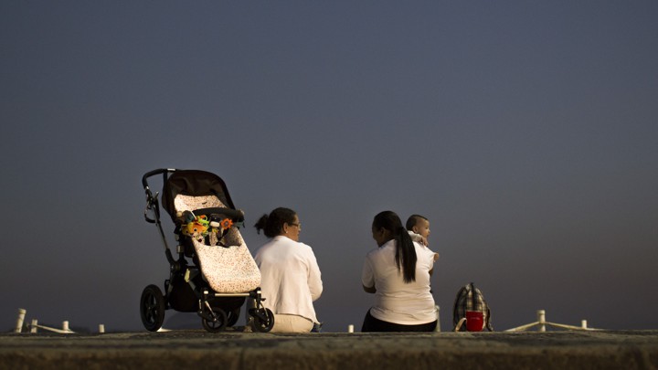 Two domestic workers chat as they take care of a baby at Leblon beach in Rio de Janeiro, Brazil.