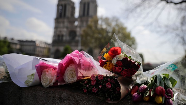 Flowers are laid on a bridge in front of the Notre-Dame cathedral a day after a fire devastated the building.