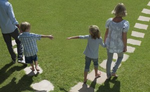 A man and woman lead two small children away from each other by the hand.