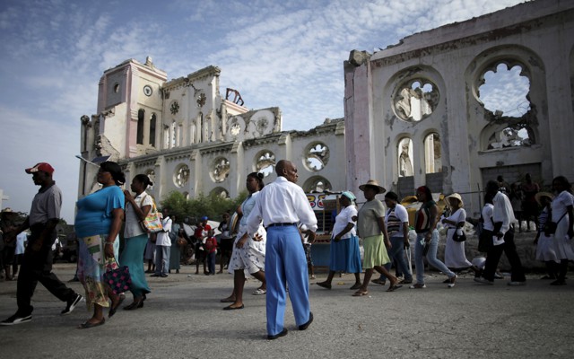 A procession walks past the ruins of the Notre-Dame de l'Assomption cathedral, destroyed in the 2010 earthquake.