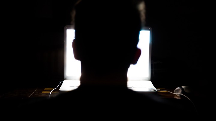 Man sitting in front of a laptop computer in the dark