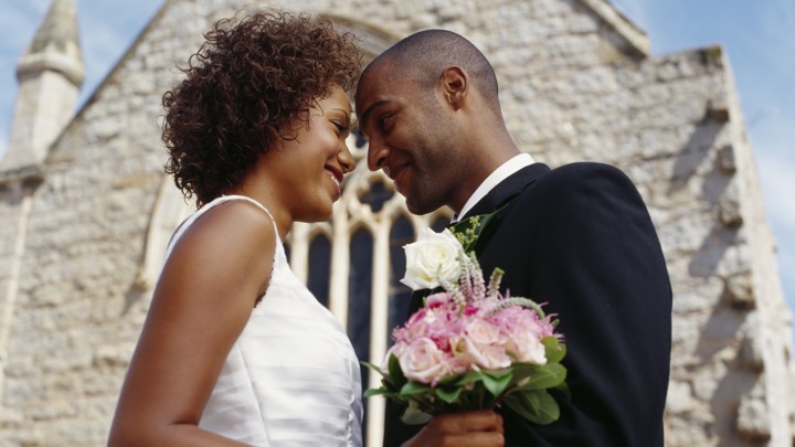 A bride and groom embrace outside a chapel.