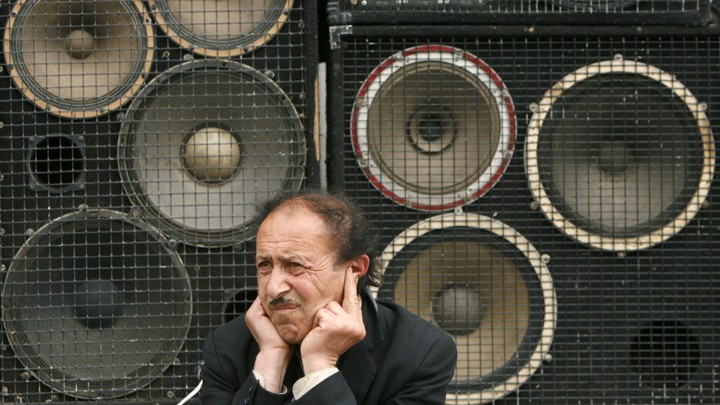 A man protects his ears as he sits in front of loudspeakers in central Yerevan in 2007.