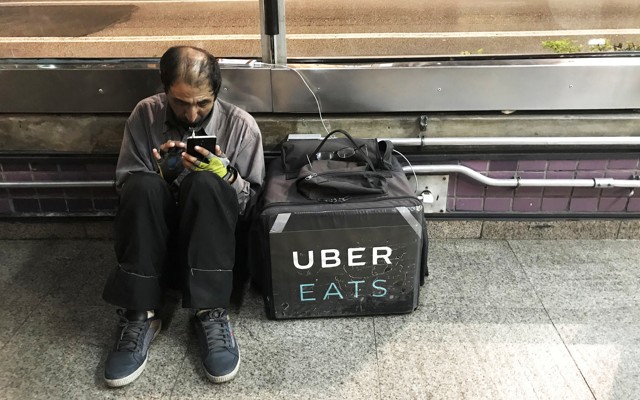 An Uber Eats worker checks his mobile phone in São Paulo.