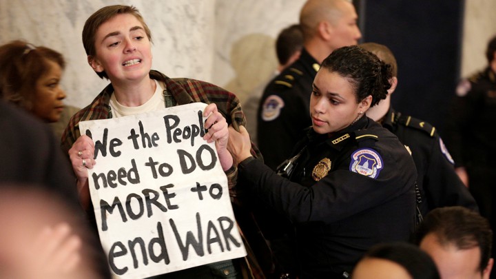 A protester holds a sign that says "We the people need to do more to end war."