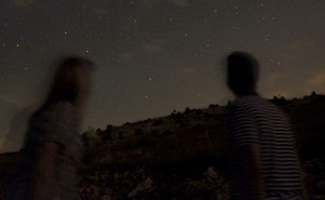 Two blurry figures look at the stars.