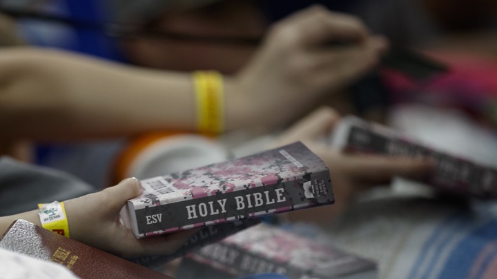 People hold out Bibles for President Donald Trump and his wife, Melania, to sign as they visit Providence Baptist Church in Smiths Station, Alabama.